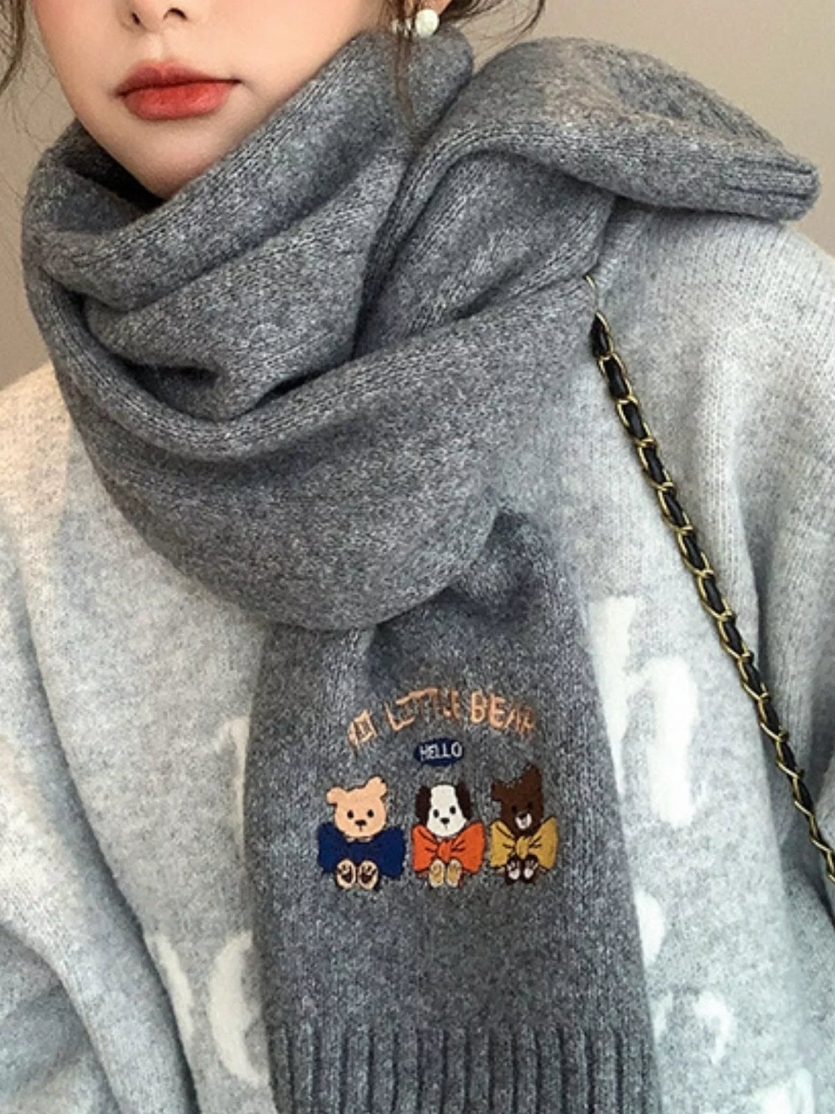 Cartoon embroidered scarf shown in a soft neutral tone