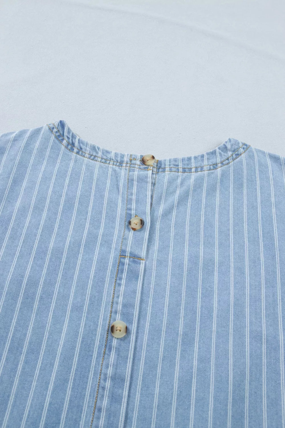 Light blue striped button back denim mini dress, angled view
