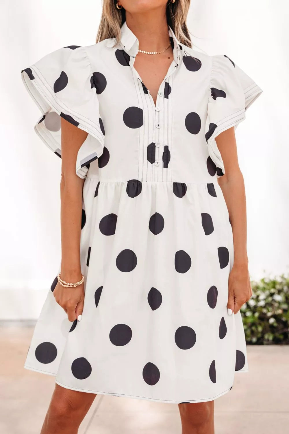 Woman wearing white polka dot ruffle mini dress front view