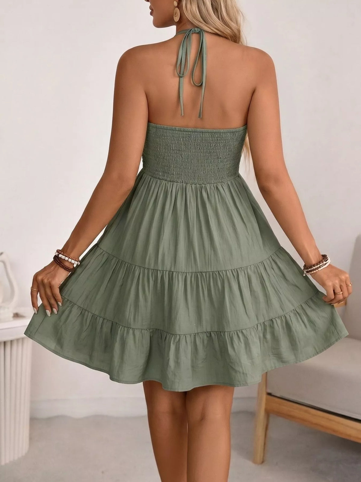 Green halter neck tiered mini dress, on model
