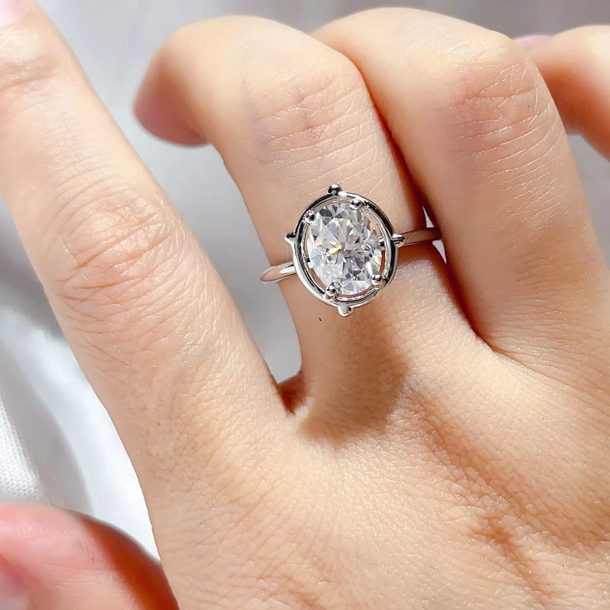 Silver oval solitaire moissanite ring worn on the hand