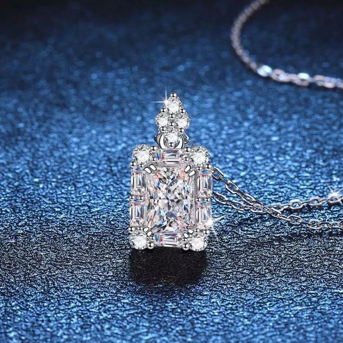 Moissanite halo pendant necklace in sterling silver on a blue background