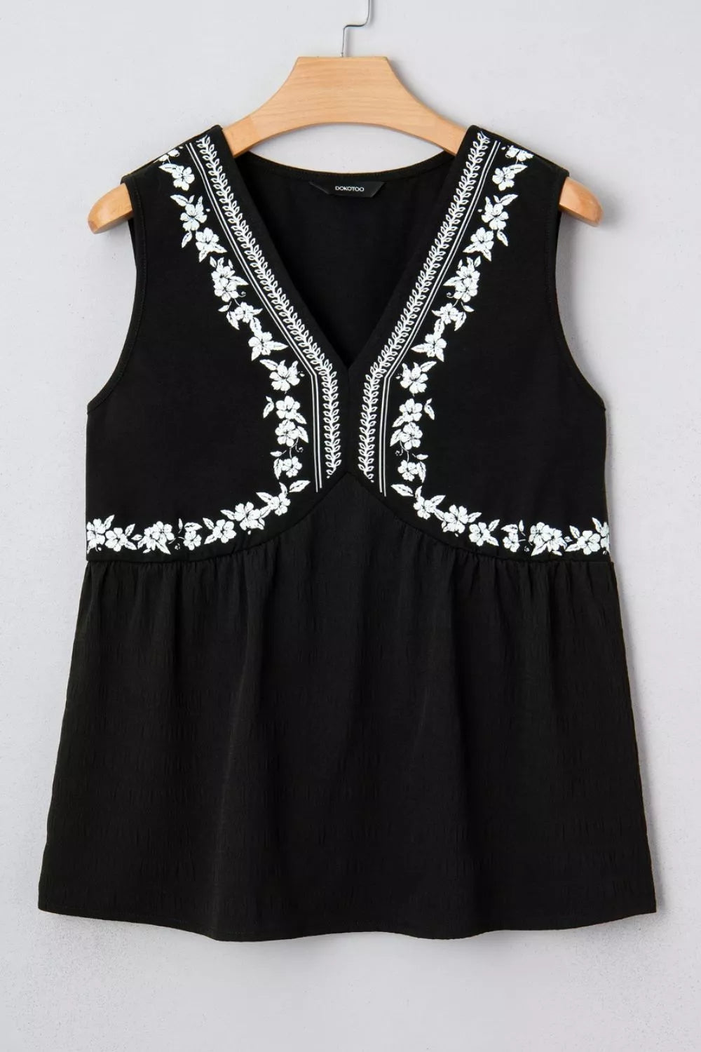 Black embroidered V neck top photographed outdoors in daylight