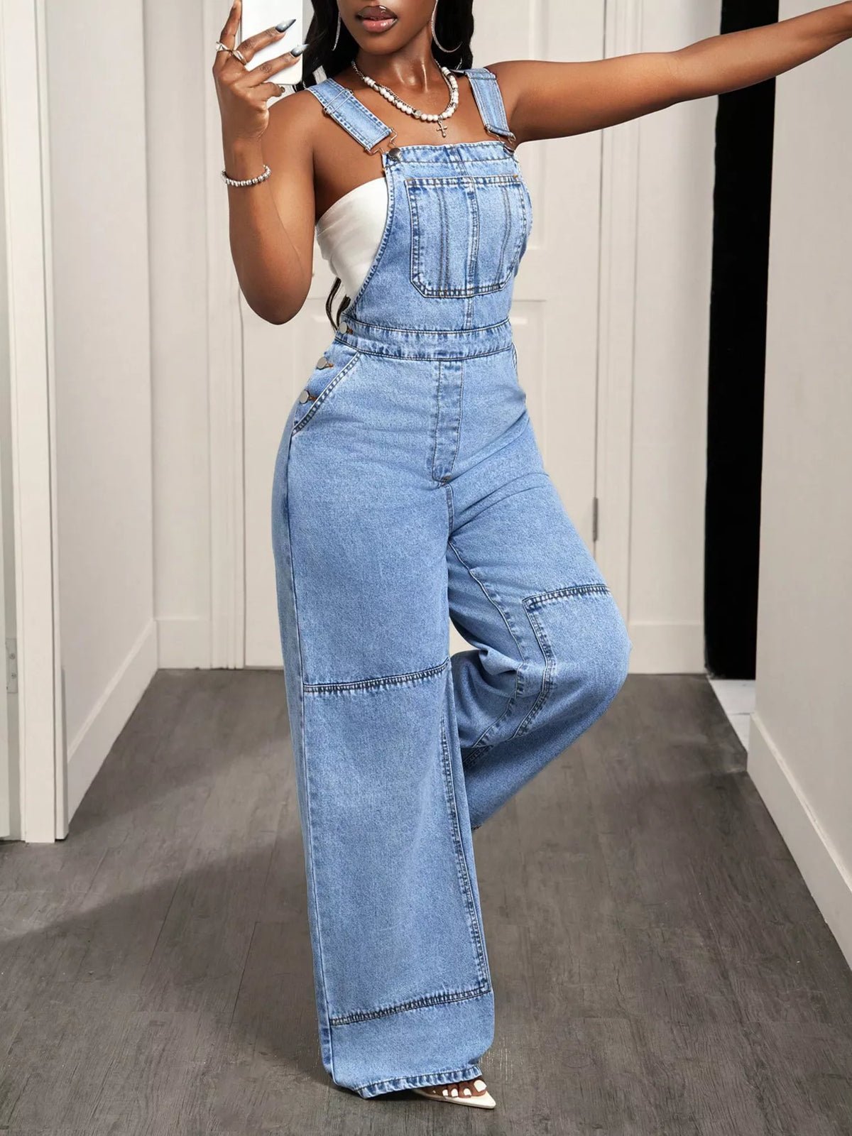 Close up of the wide strap and buckle on denim overalls