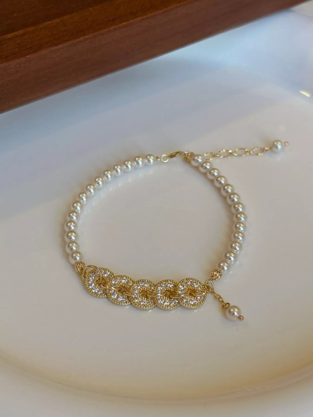 Gold plated pearl and coin charm bracelet on white background