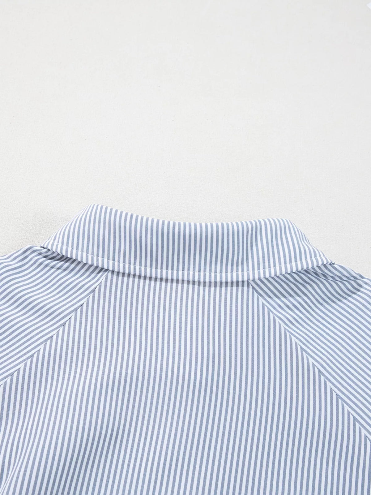Close view of the hem on the pinstripe blouse