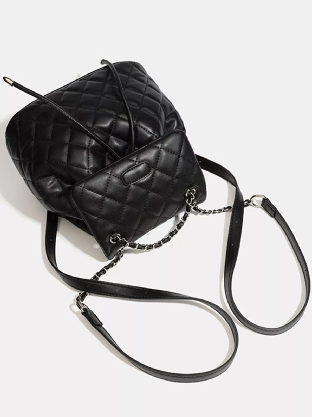 Black quilted chain flap backpack worn on the shoulders