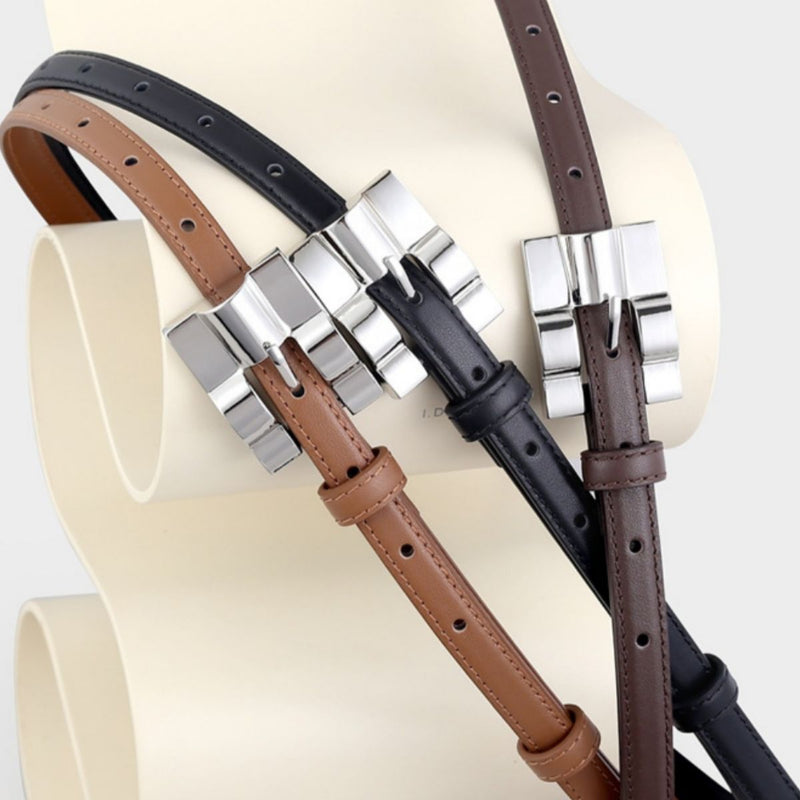 Skinny leather belt with silver buckle coiled