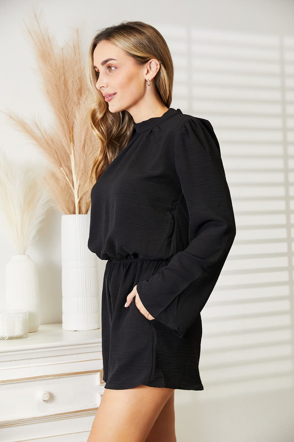Model wearing the black open back romper outdoors