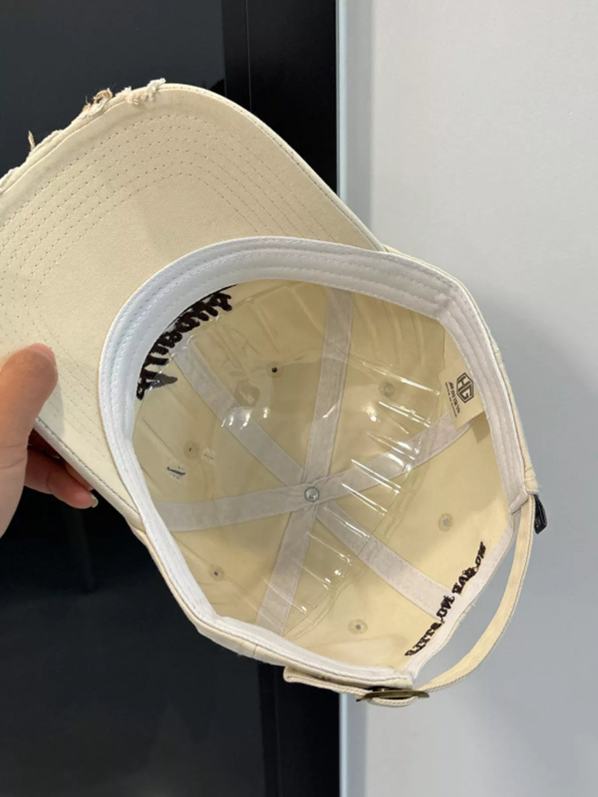 Distressed finish detail on the beige baseball cap
