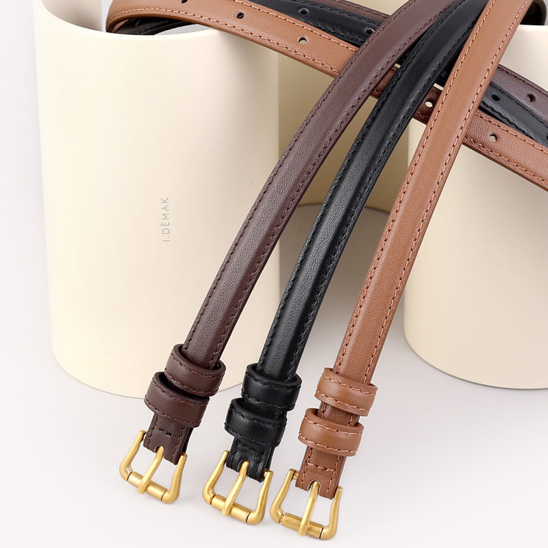 Skinny leather belt with gold buckle coiled