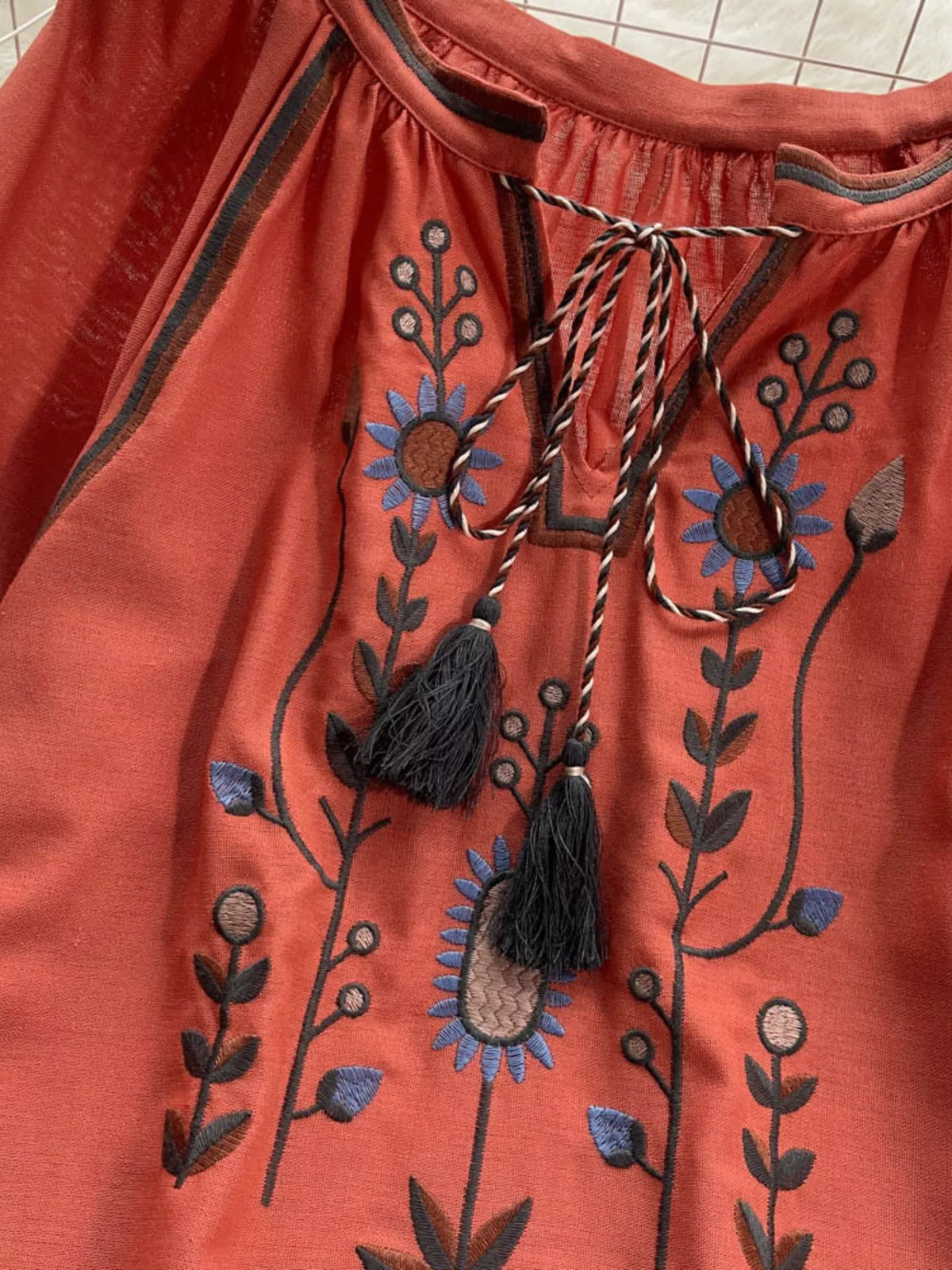 Tassel detail swinging from the tie neck of the blouse