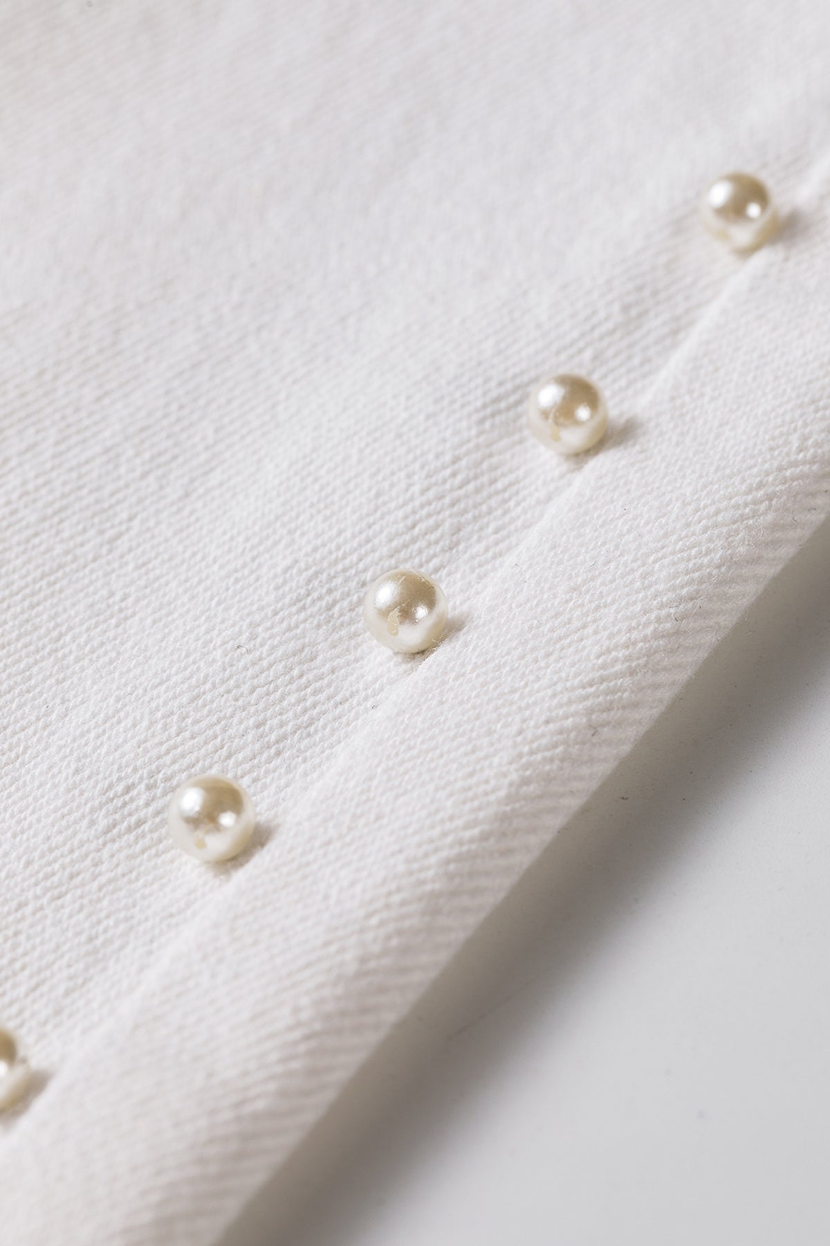 Ankle length hem and pearl detail on white flare jeans