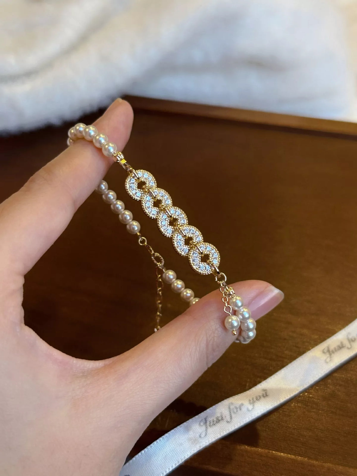 Gold plated pearl and coin charm bracelet on white background
