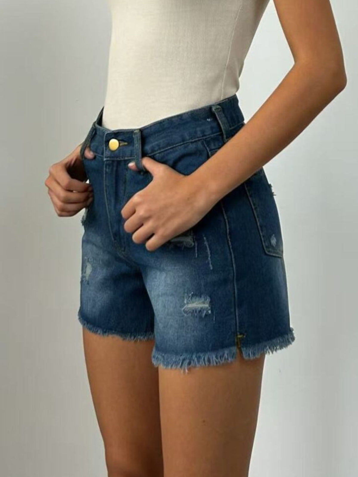 Distressed jean shorts worn with sandals, full length look