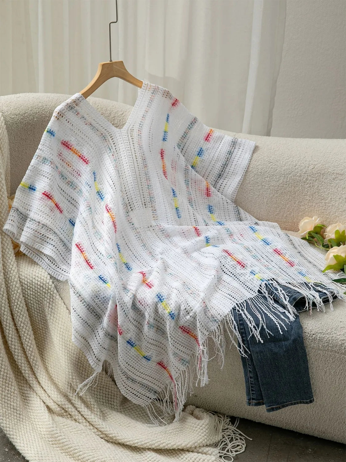 Fringe hem detail on white knit cape