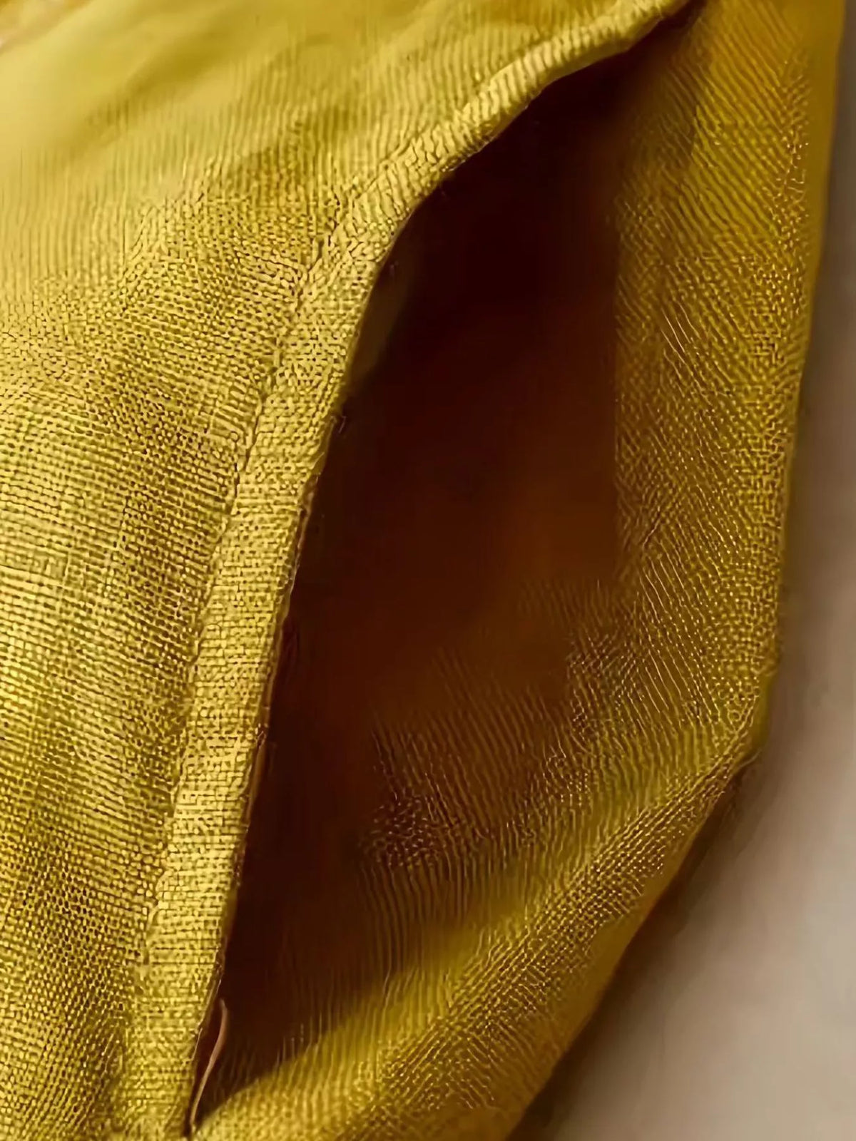 Close view of the decorative buttons and high waist on the yellow pants