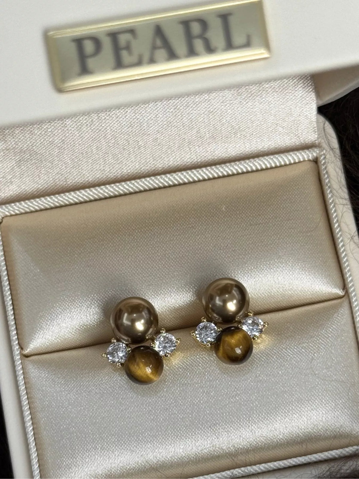 Tiger eye and pearl earrings on ear view