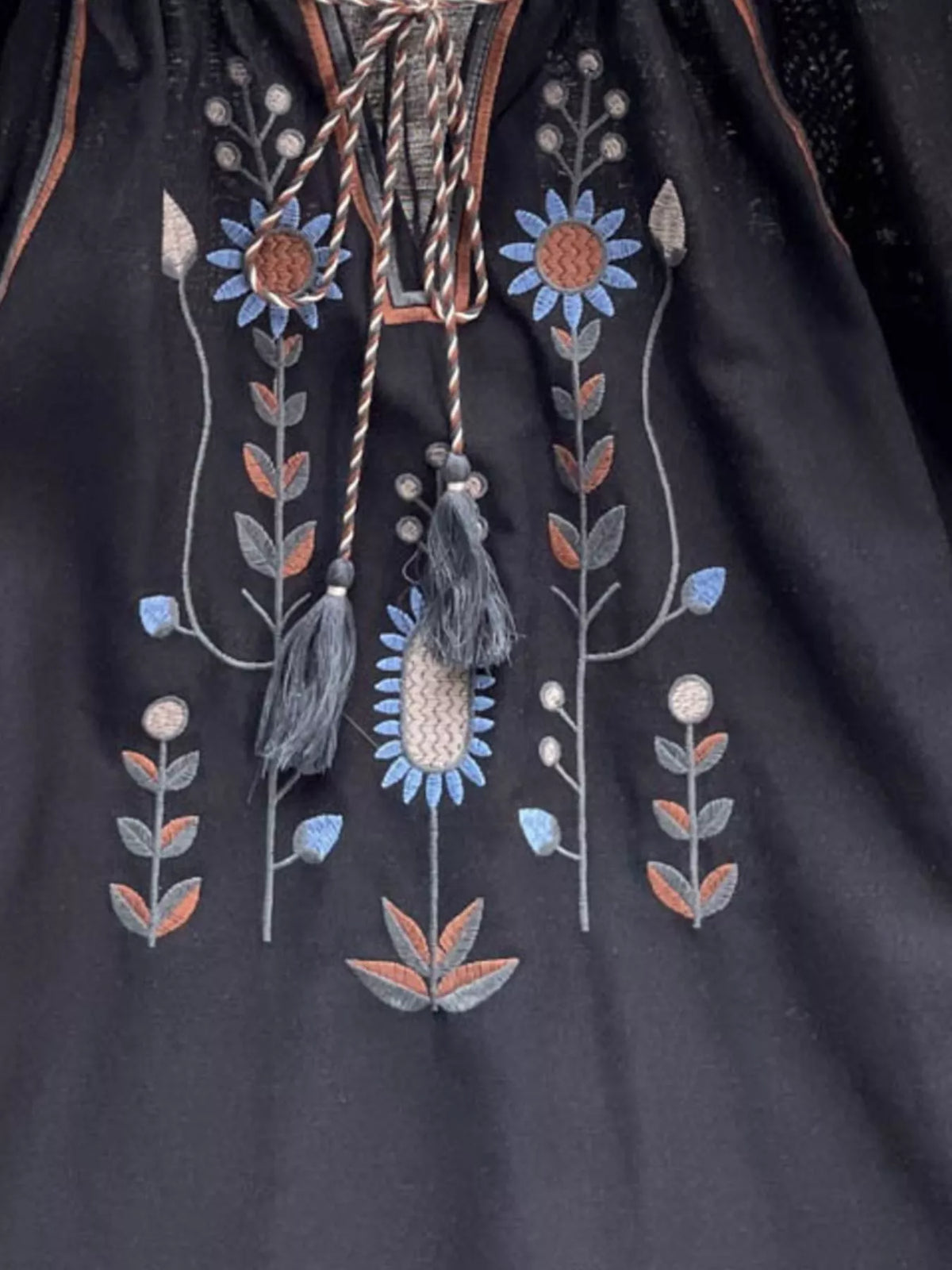 Black embroidered tassel blouse shown on model, side angle