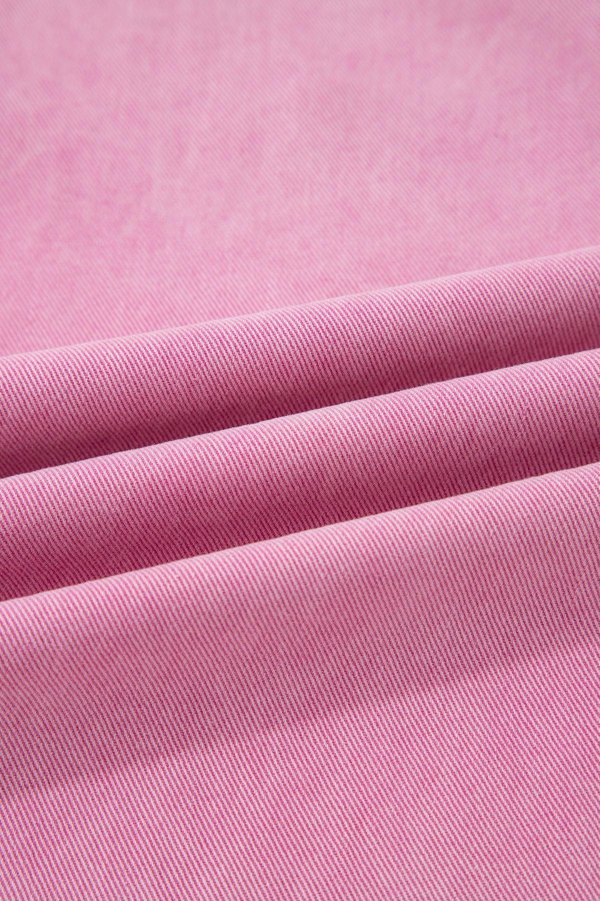 Cotton denim fabric close up on pink jeans