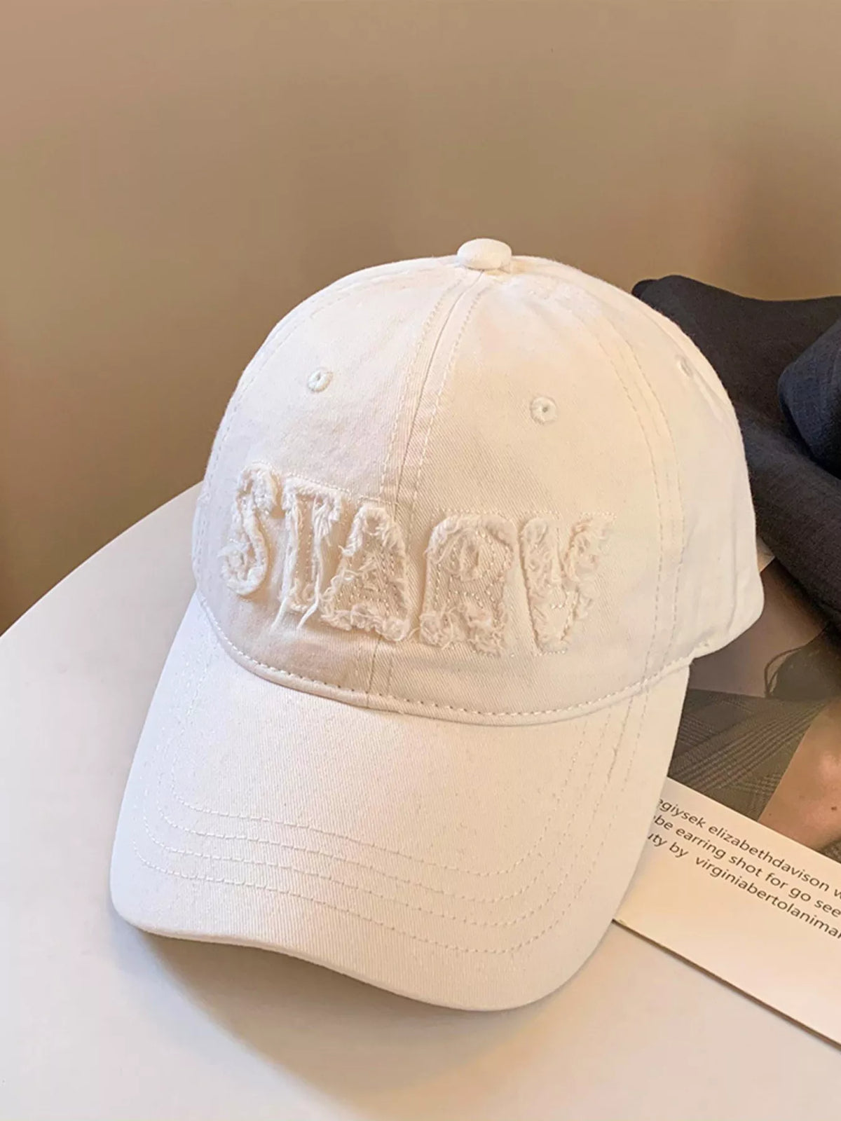 Close up of frayed letter embroidery detail on cap