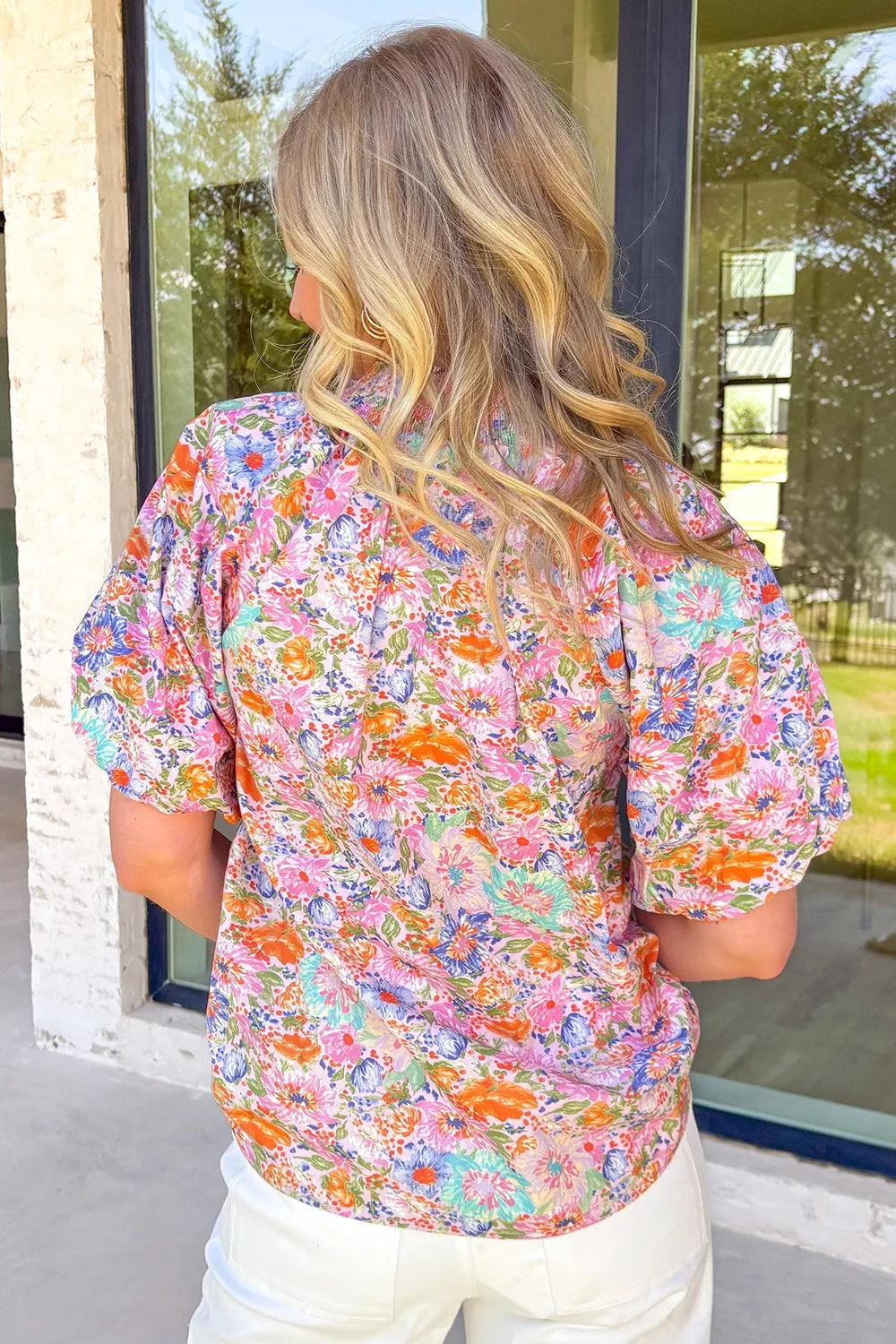 Model wearing floral print blouse tucked into trousers