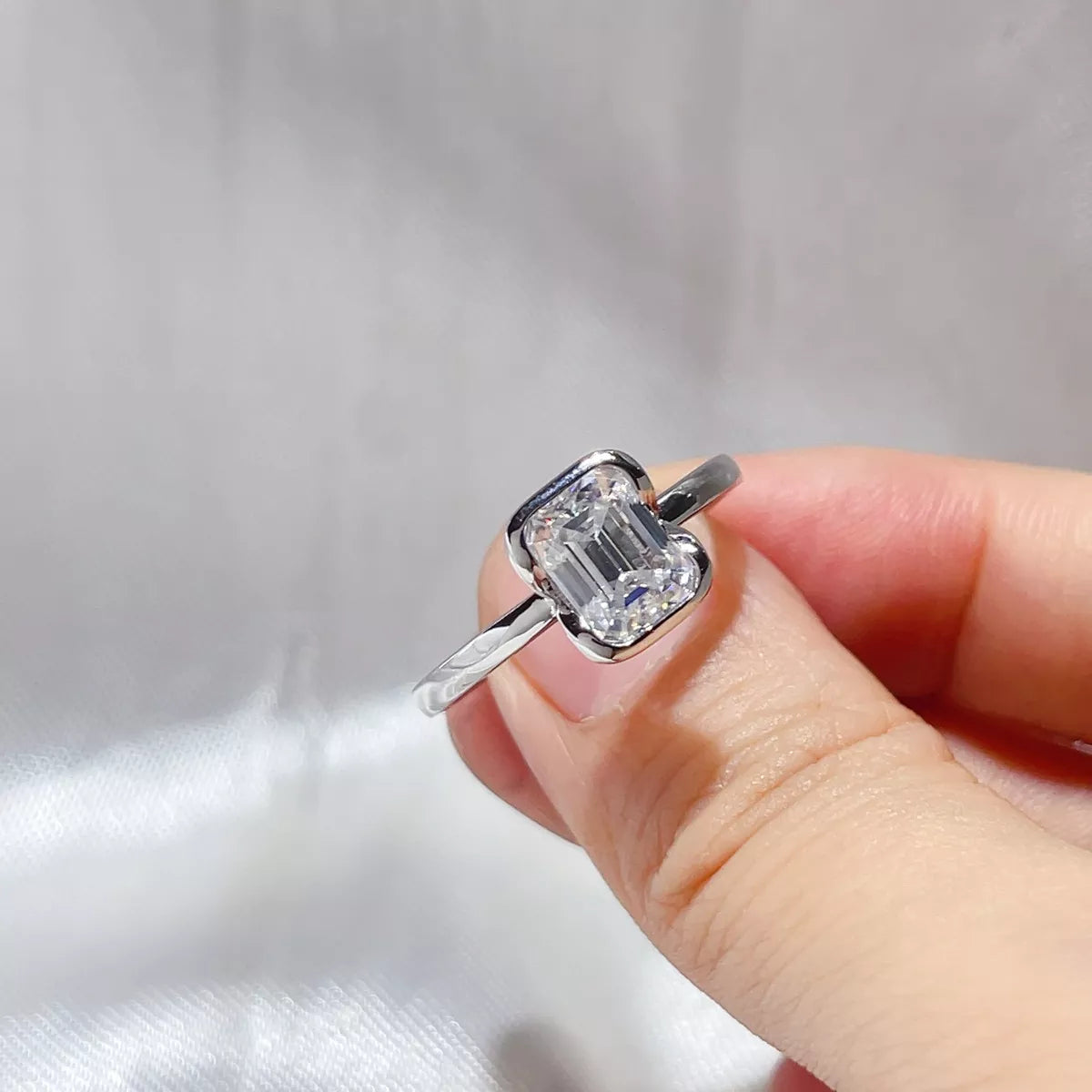 Emerald cut moissanite sterling silver ring worn on the hand