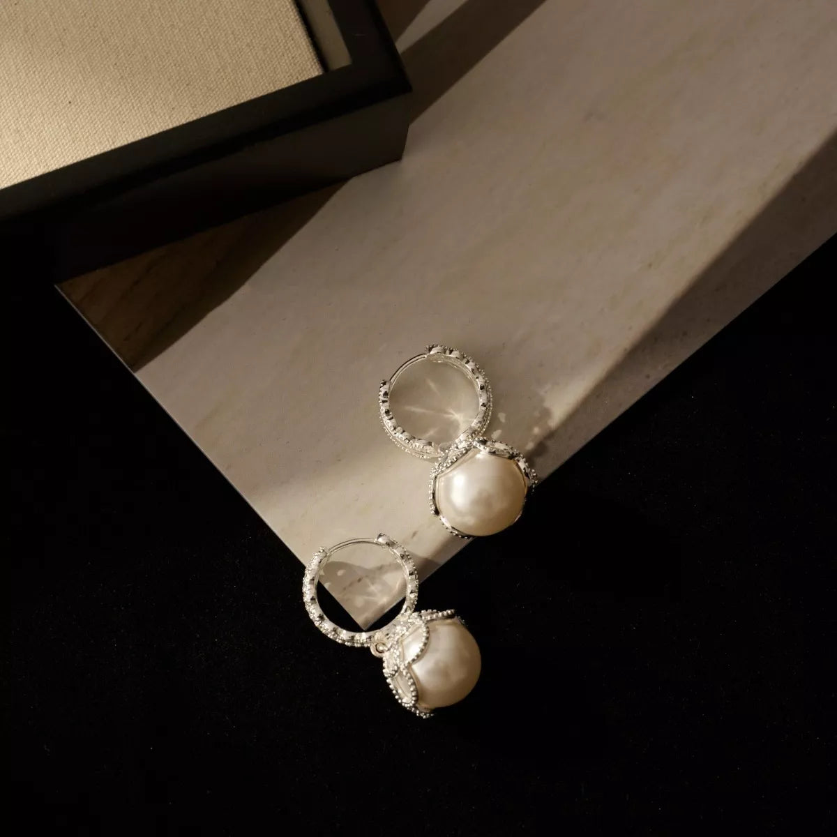 Pearl hoop earrings with zircon accents in silver tone, front view