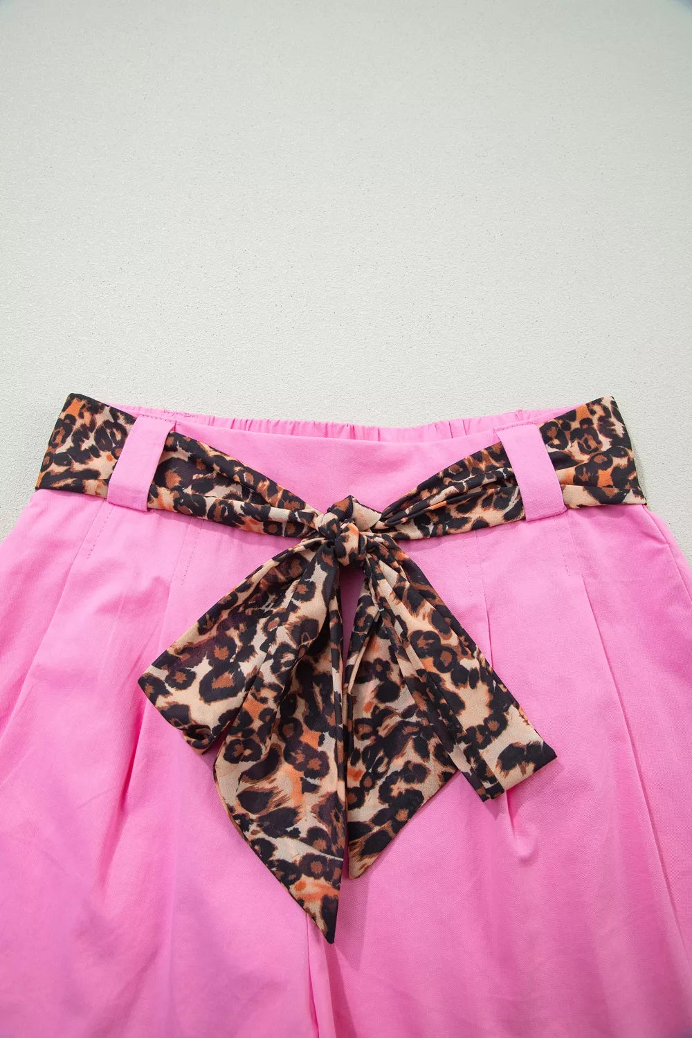 Fuchsia pink pleated wide leg shorts with leopard sash belt full length view