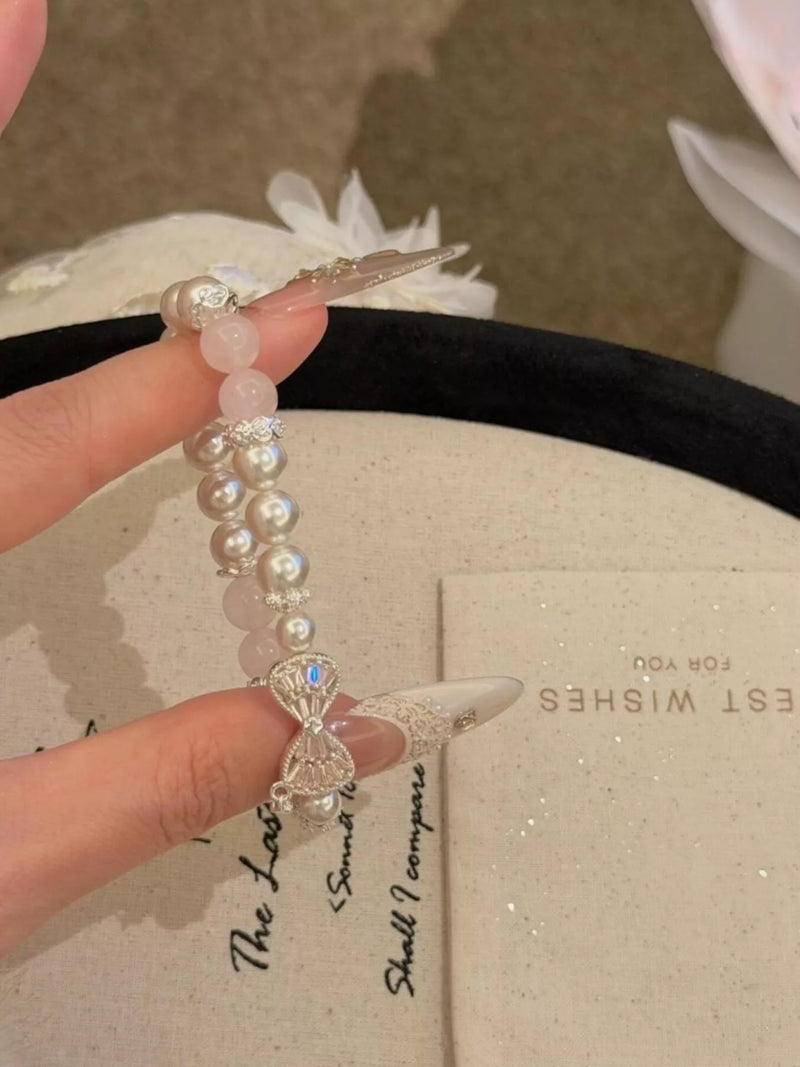 Silver bow charm pearl bracelet on wrist