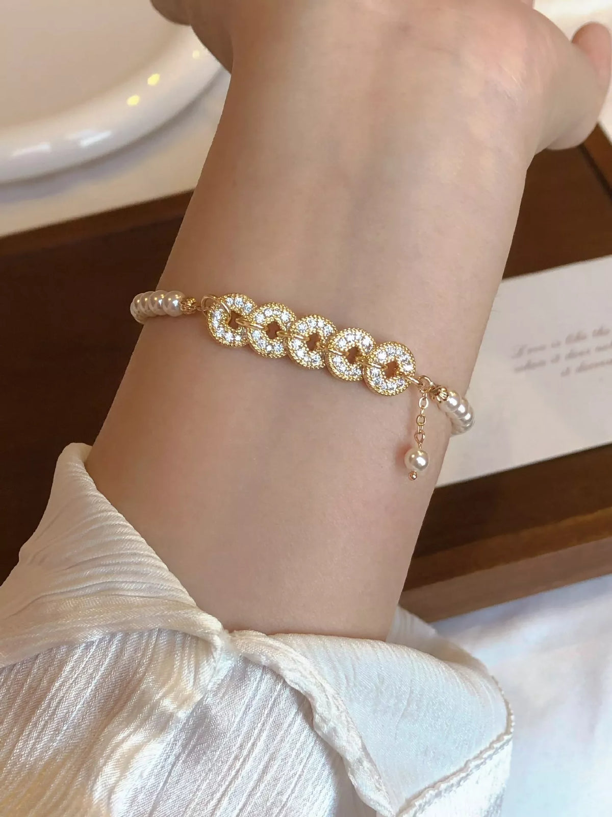 Gold plated pearl and coin charm bracelet on white background