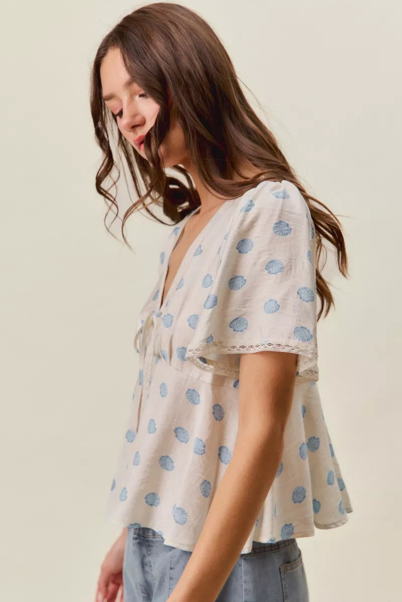 Ivory and blue shell print tie front flutter sleeve blouse back view