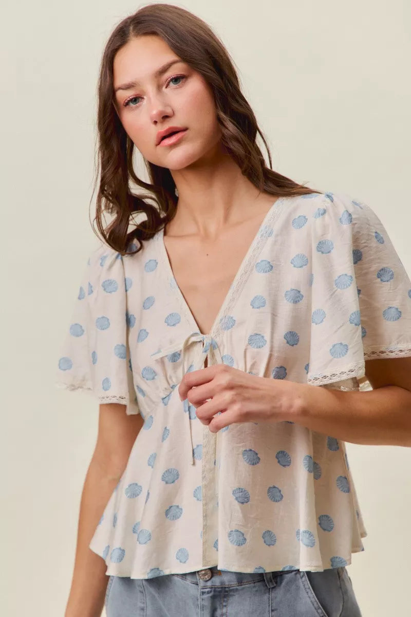 Ivory and blue shell print tie front flutter sleeve blouse close up view