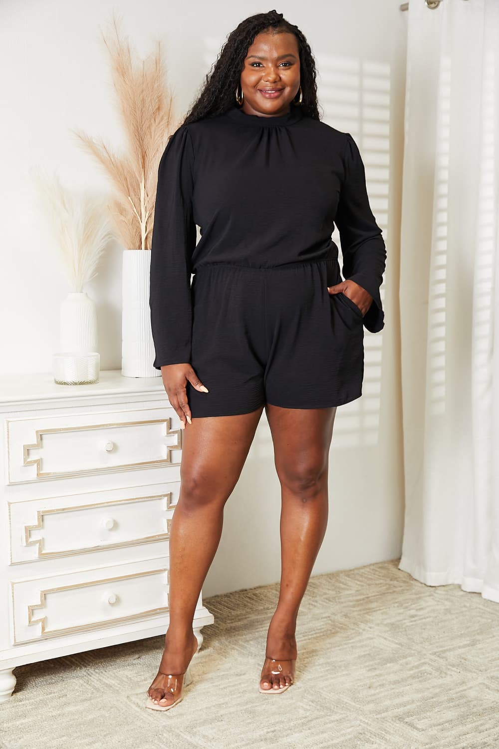 Full length view of the black open back romper on model