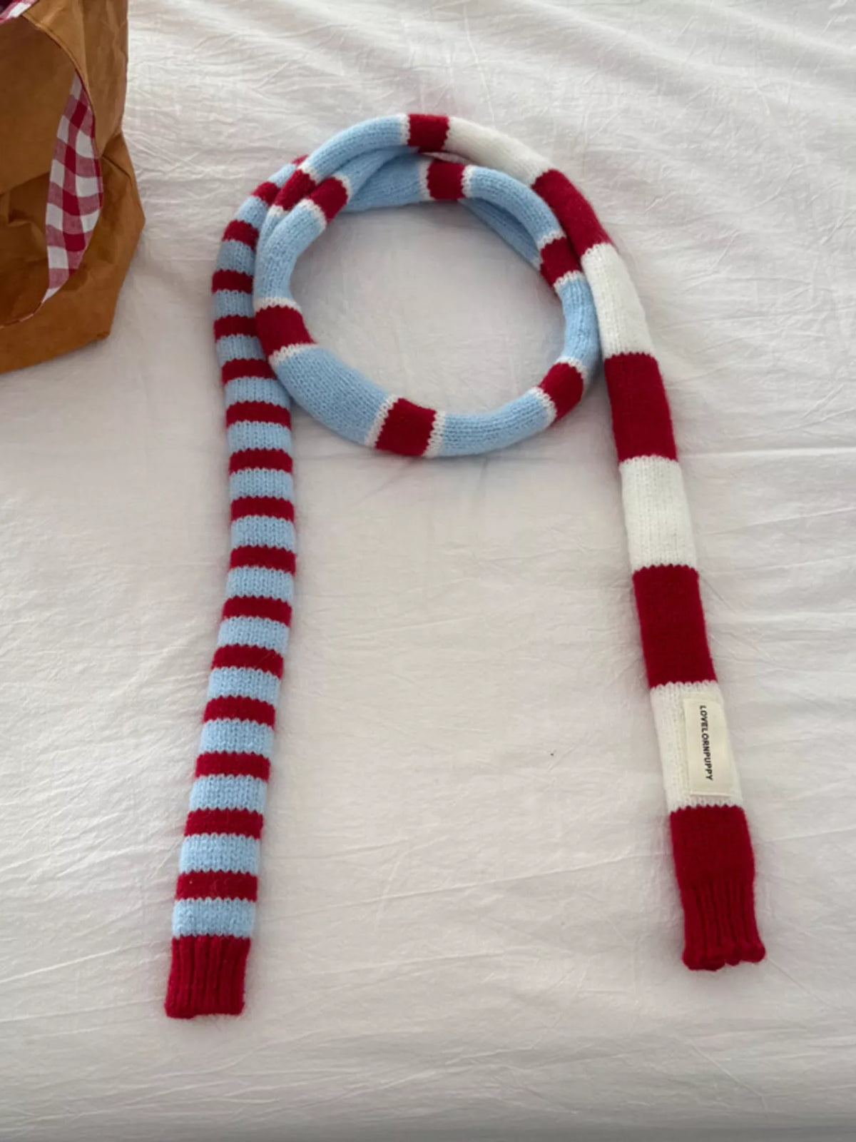 Knitted striped scarf styled over a coat