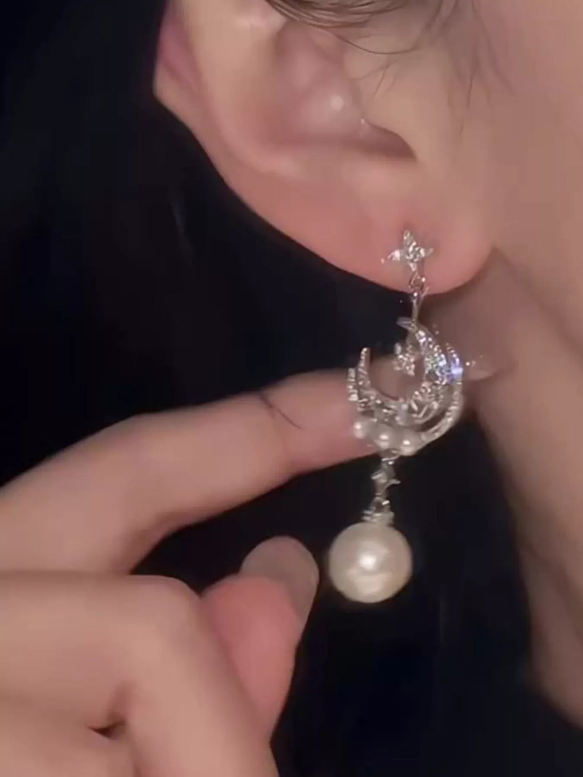 Moon and star pearl dangle earrings in silver tone, styled outfit