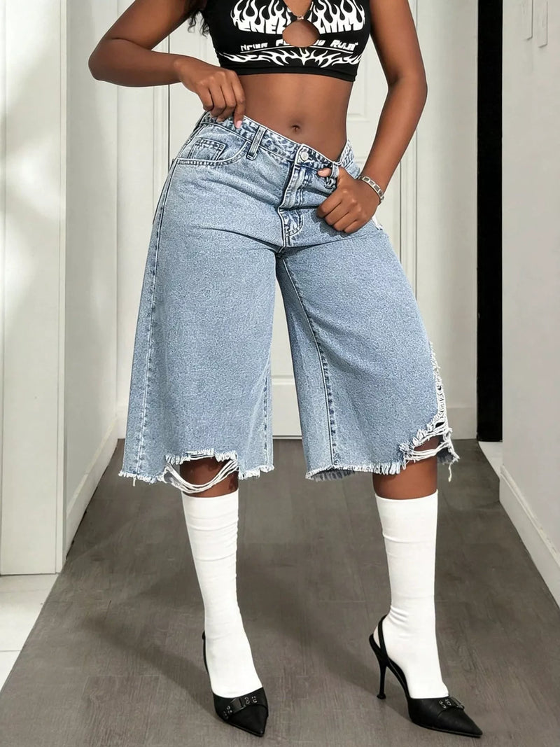 Light blue distressed wide leg shorts worn with a cropped top and heeled boots