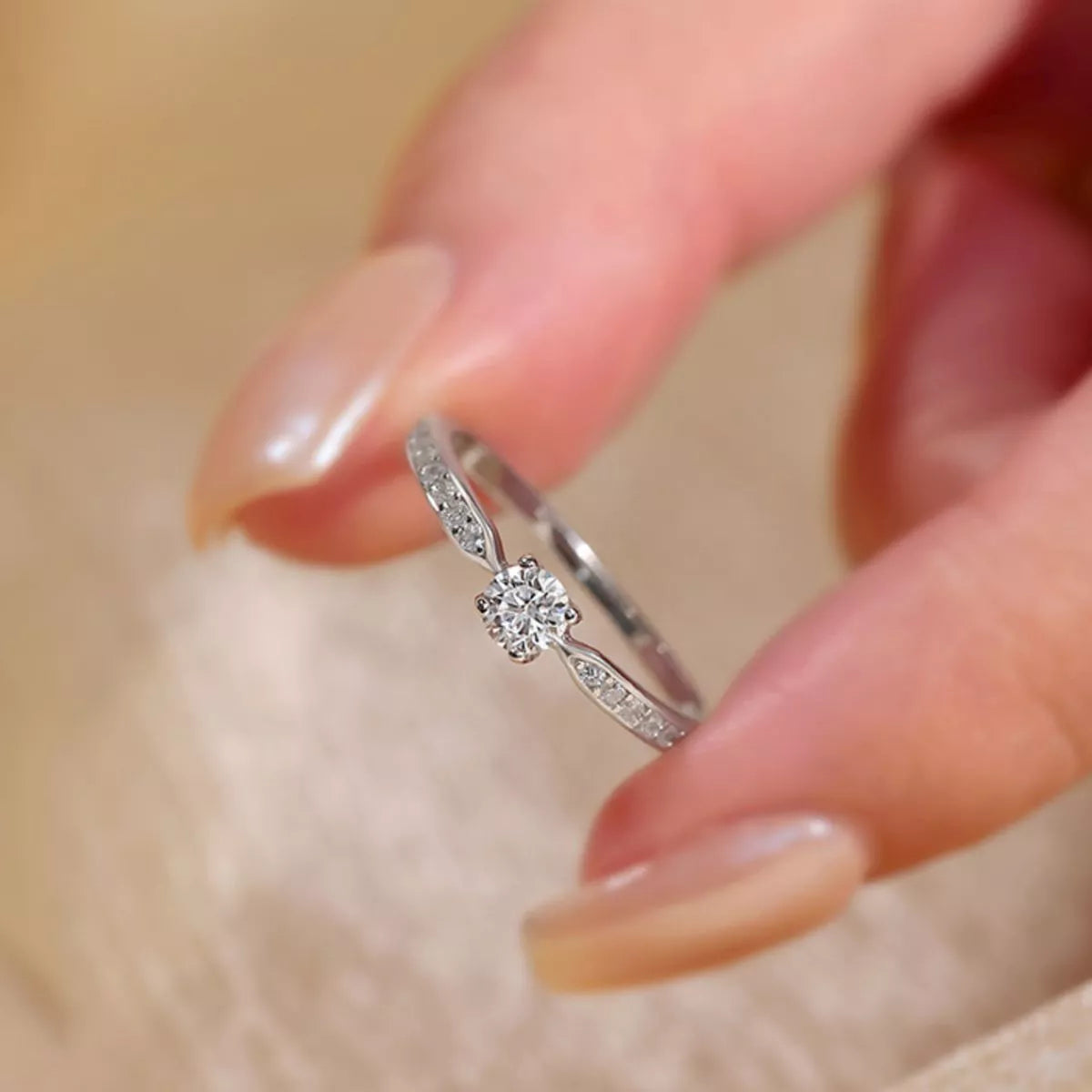 Adjustable silver ring shown against a plain surface
