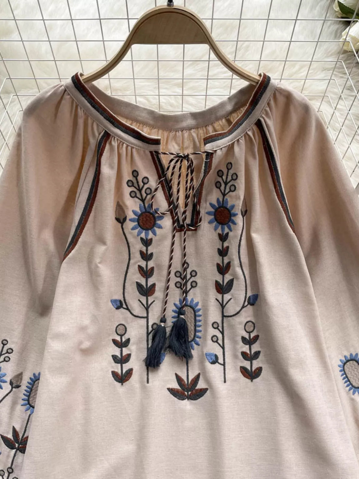 Embroidery detail across the body of the tie neck blouse