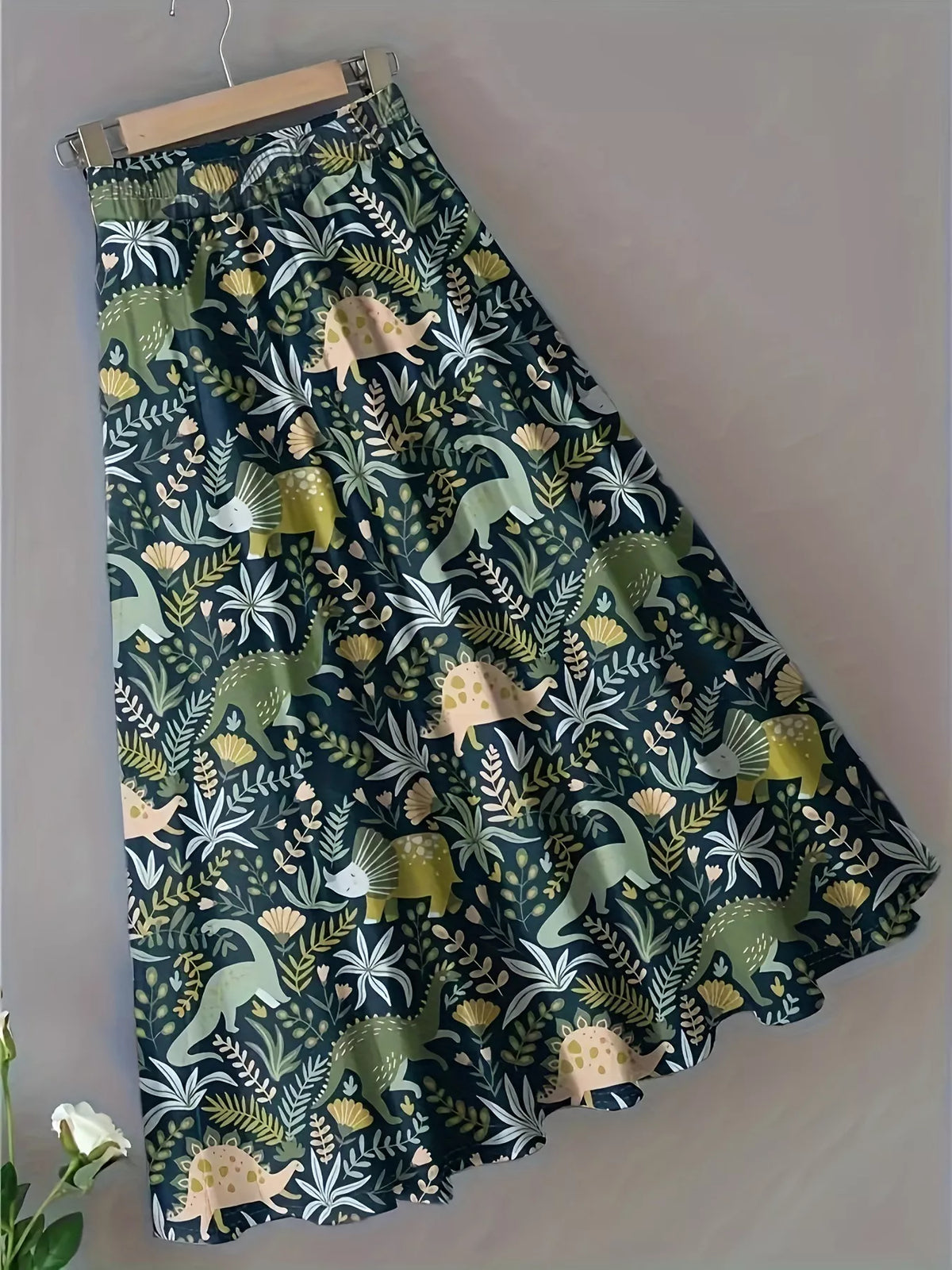 Dinosaur print midi skirt shown on a hanger against a plain wall