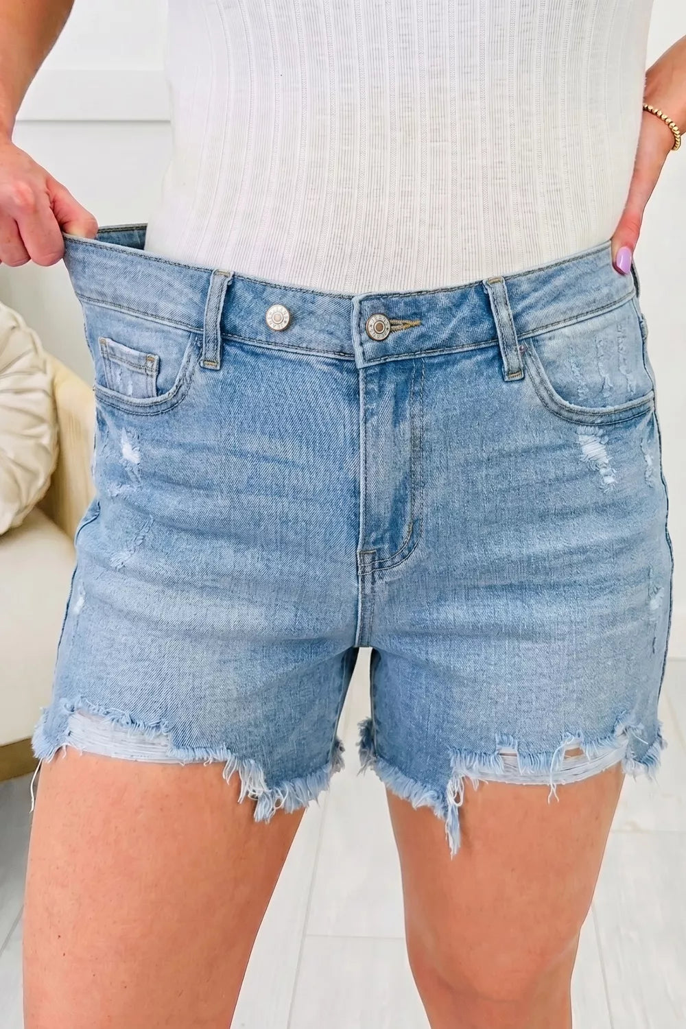 Medium wash distressed raw hem denim shorts front view