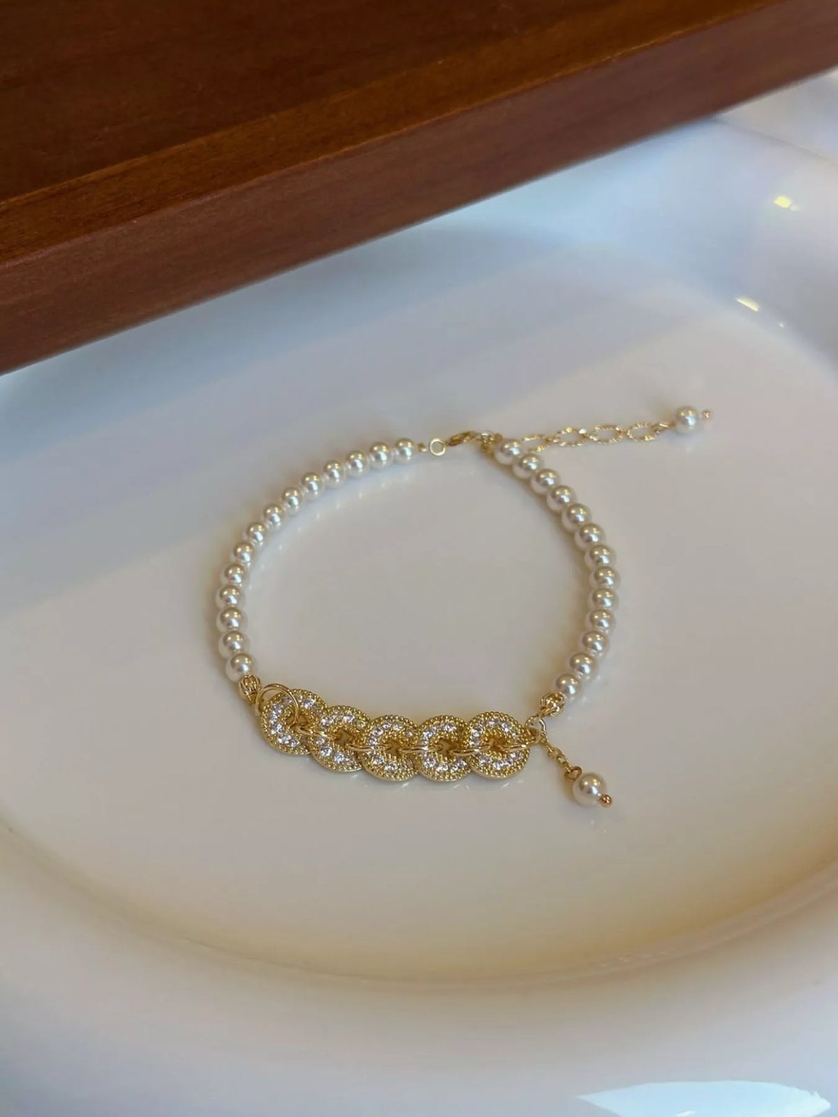 Gold plated pearl and coin charm bracelet on white background
