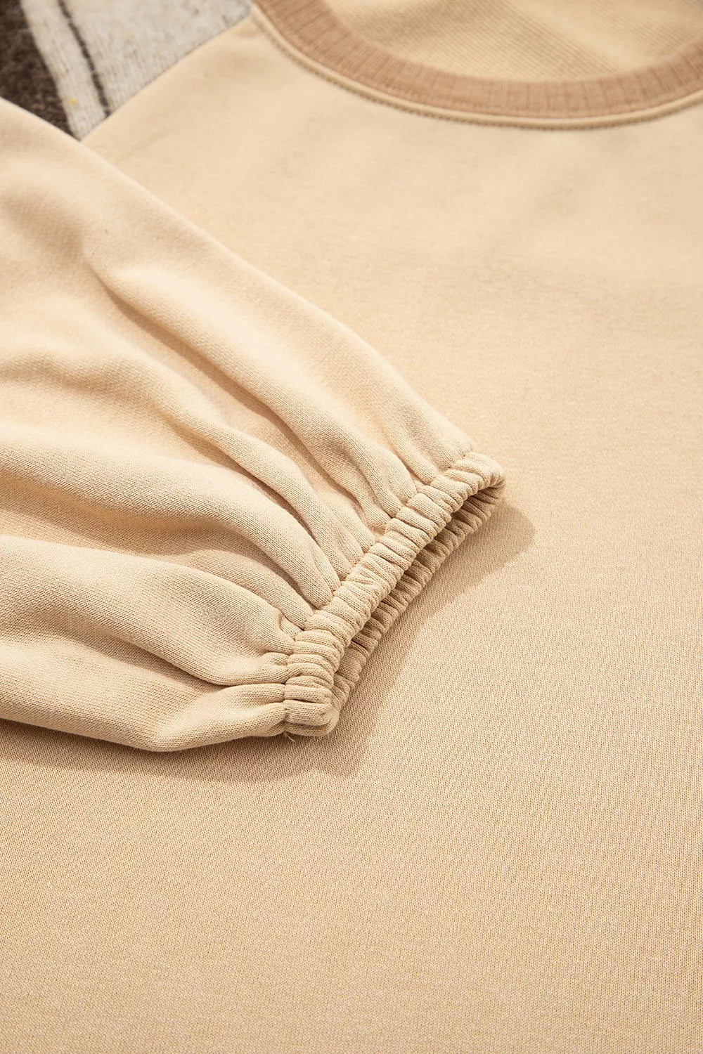 Close up of the tan sweatshirt fabric and patchwork stitching