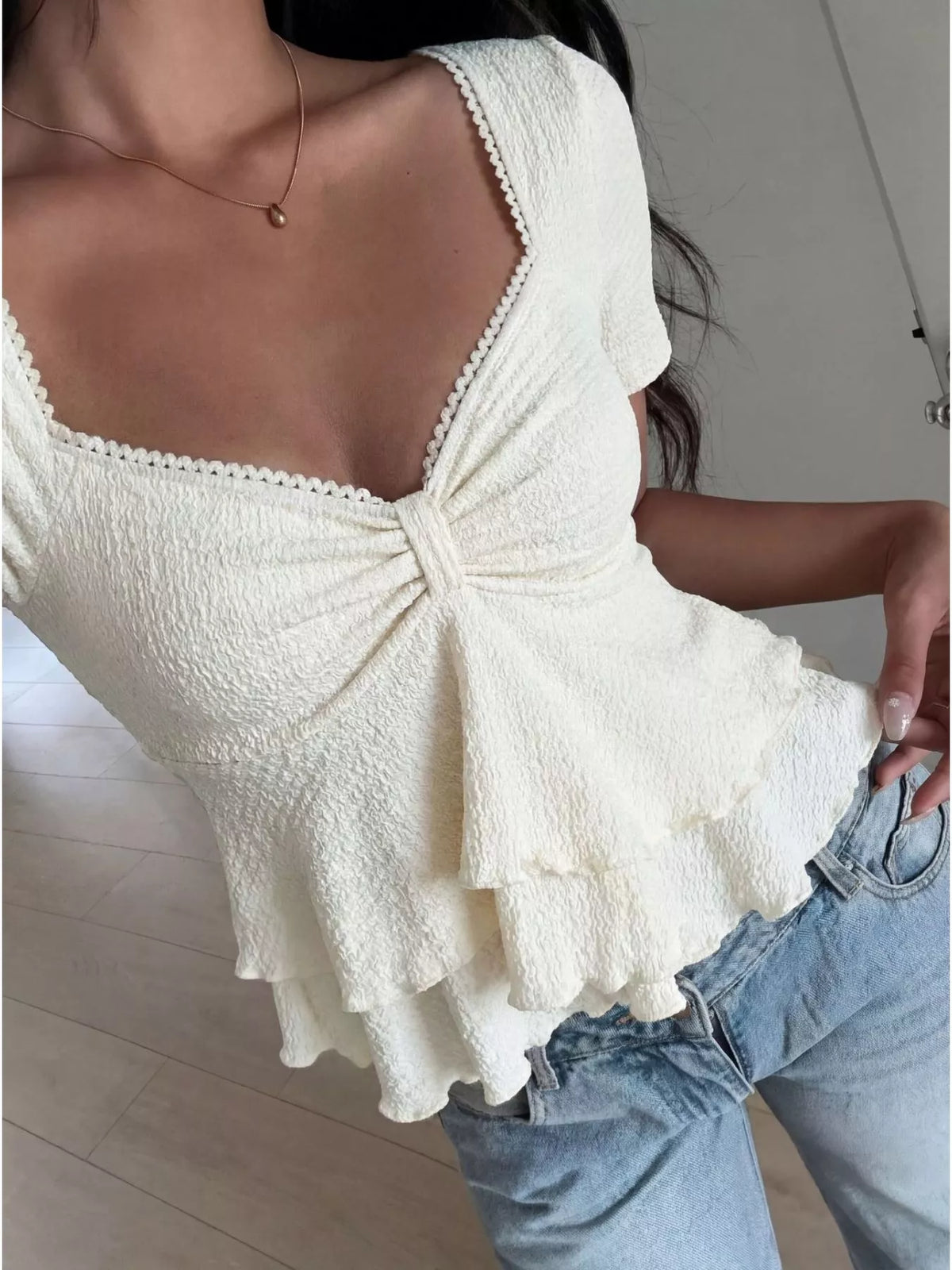 Side view showing the ruched body of the white ruffle top