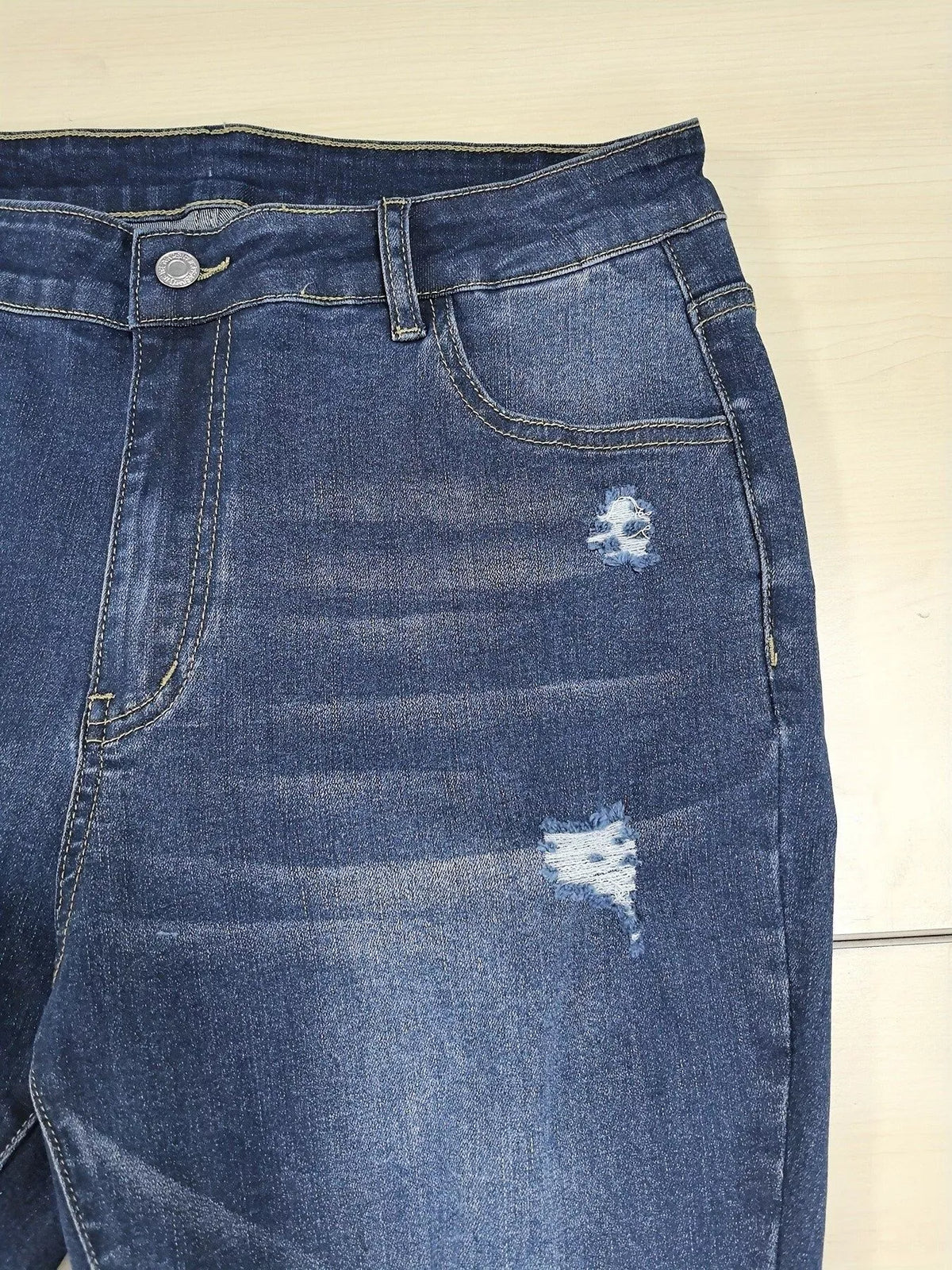 Raw hem detail on distressed blue jeans