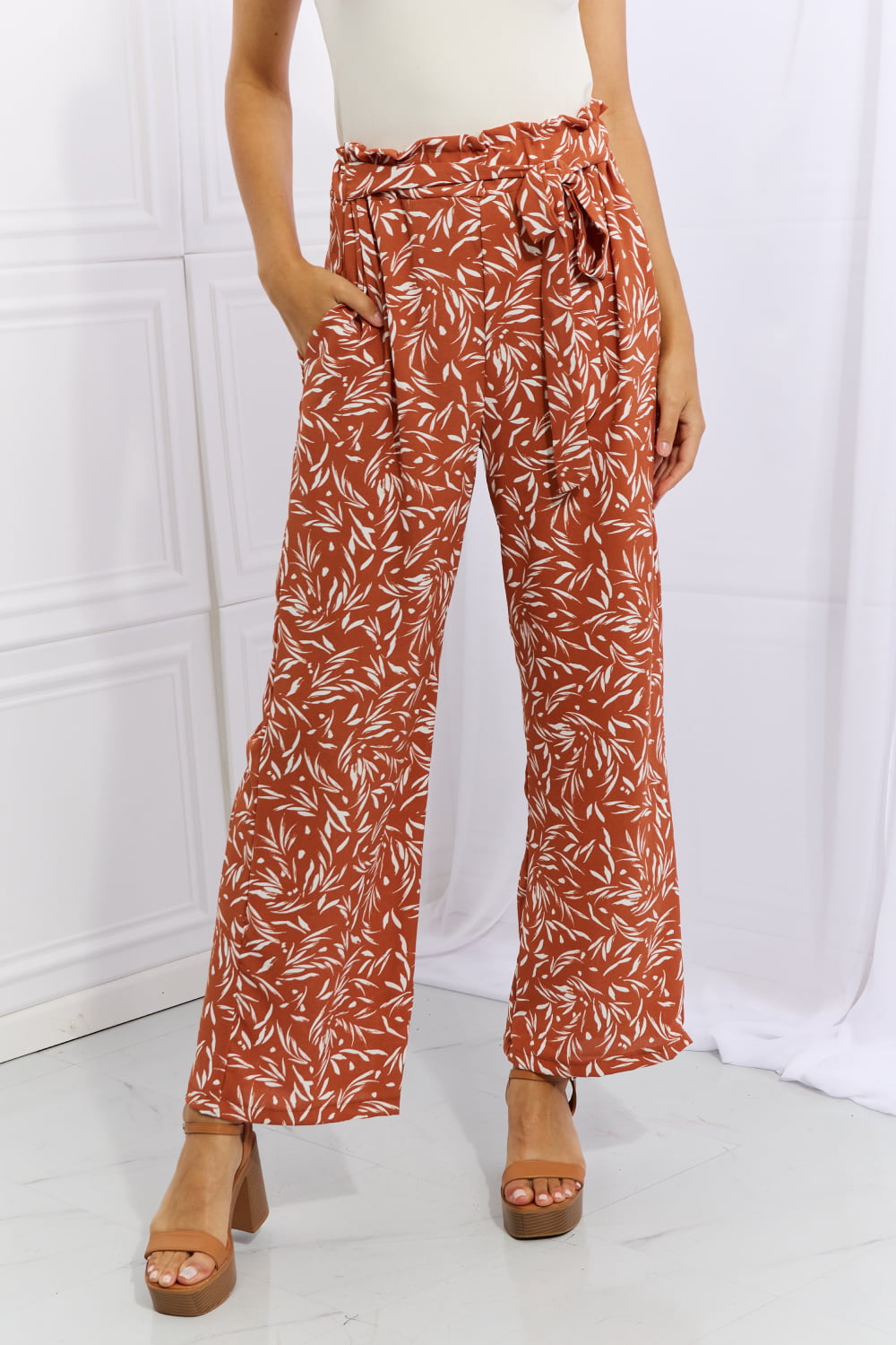 Front view of red orange geometric printed pants with paperbag waist