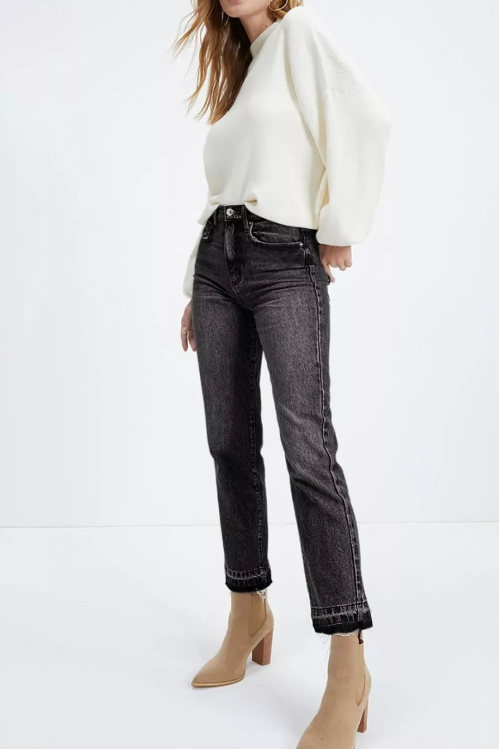Distressed raw hem detail on black straight leg jeans