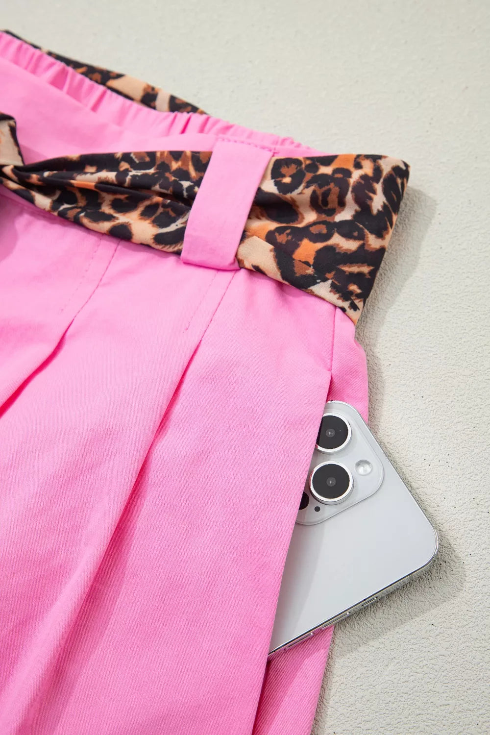 Fuchsia pink pleated wide leg shorts with leopard sash belt close up view