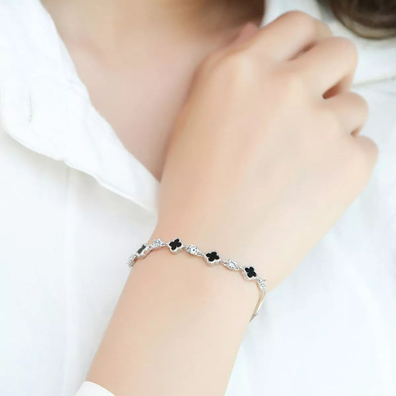 Sterling silver clover charm bracelet on a plain background