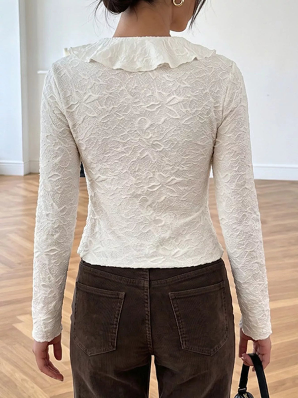 Back view of ruffled long sleeve top in apricot